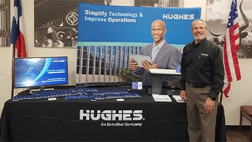 Hughes employee in front of Hughes booth