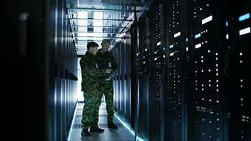 two military employees examining computer servers