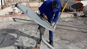 Hughes employee repairing a satellite dish