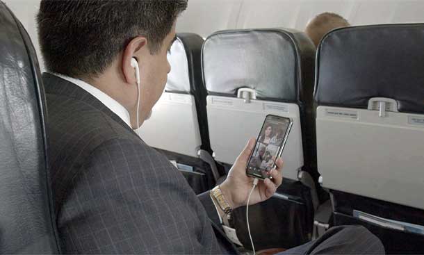 air passenger using in flight connectivity to stream tv on cell phone