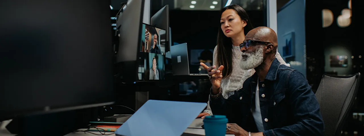 Man and woman gathered around desk on conference call
