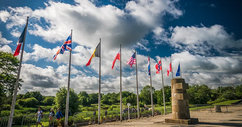 A low-angle photo shows a row of nine national flags. 