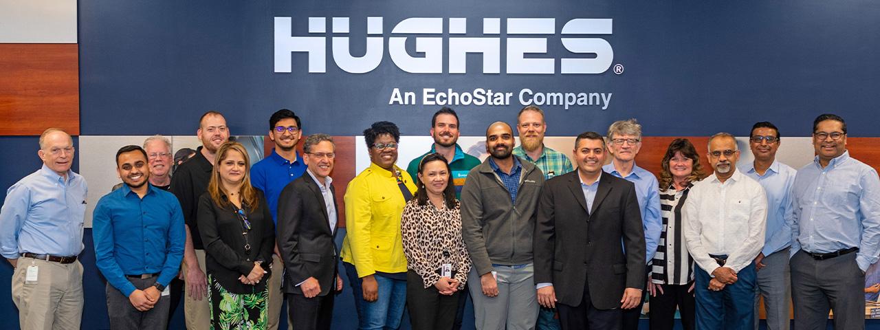 Hughes employees in front of Hughes sign