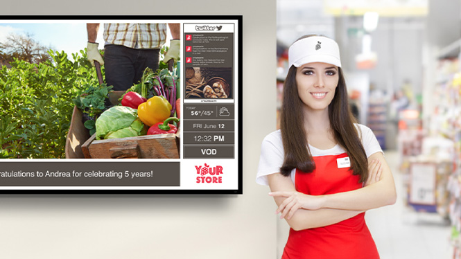 grocery employee standing next to digital signage board