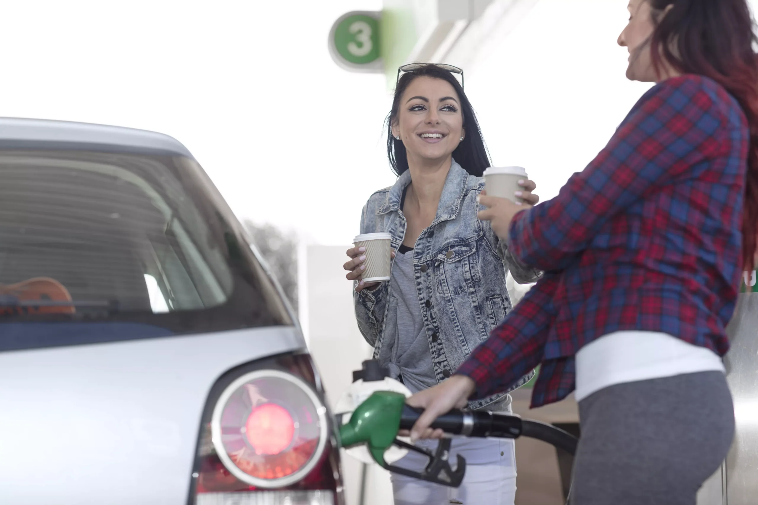 two women with coffee at a gas pump