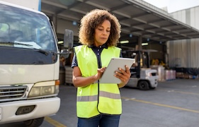 A person wearing a construction vest looking at an iPad