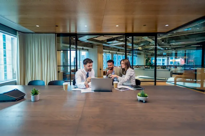 A group of people collaborating in an office looking at a laptop