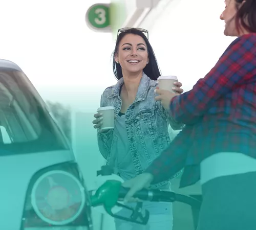 women with coffee at gas pump