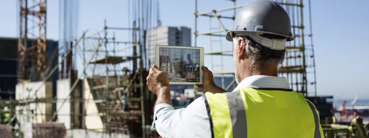 construction worker holding up connected device
