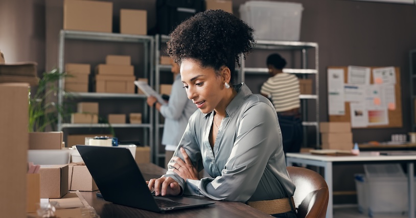 A woman at a table looking at her laptop