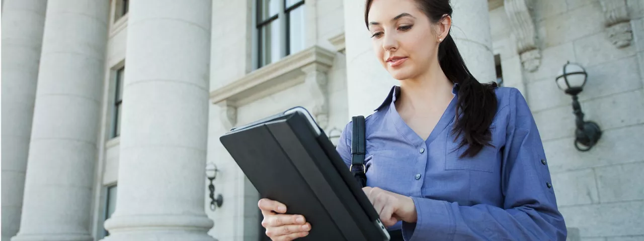 woman outside federal building on tablet
