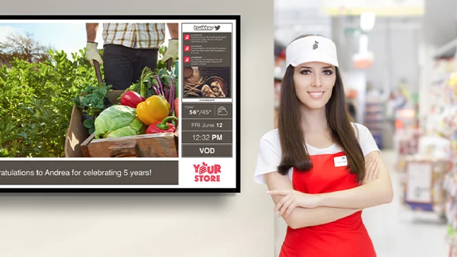 grocery employee standing next to digital signage board