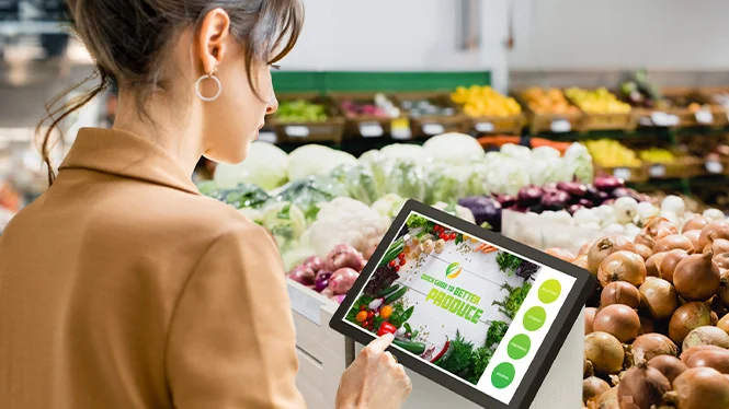 woman using grocery store kiosk in produce section