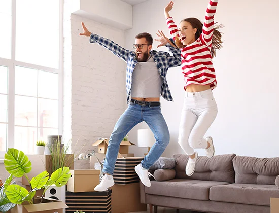 Full body of happy young family couple energetic couple having fun and jumping high while enjoying new home after relocation