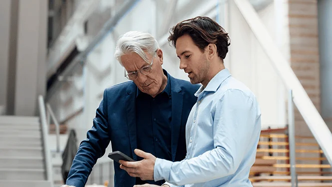 Two men looking at a phone together.