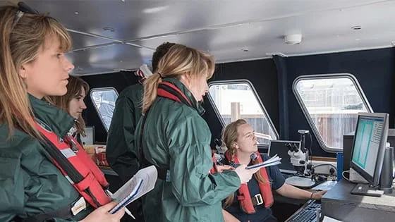 People looking at a computer on a boat