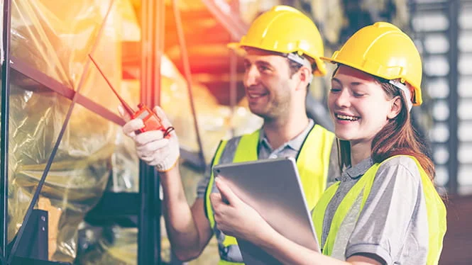 Two people in hard hats and vests looking at an Ipad and using a walkie talkie